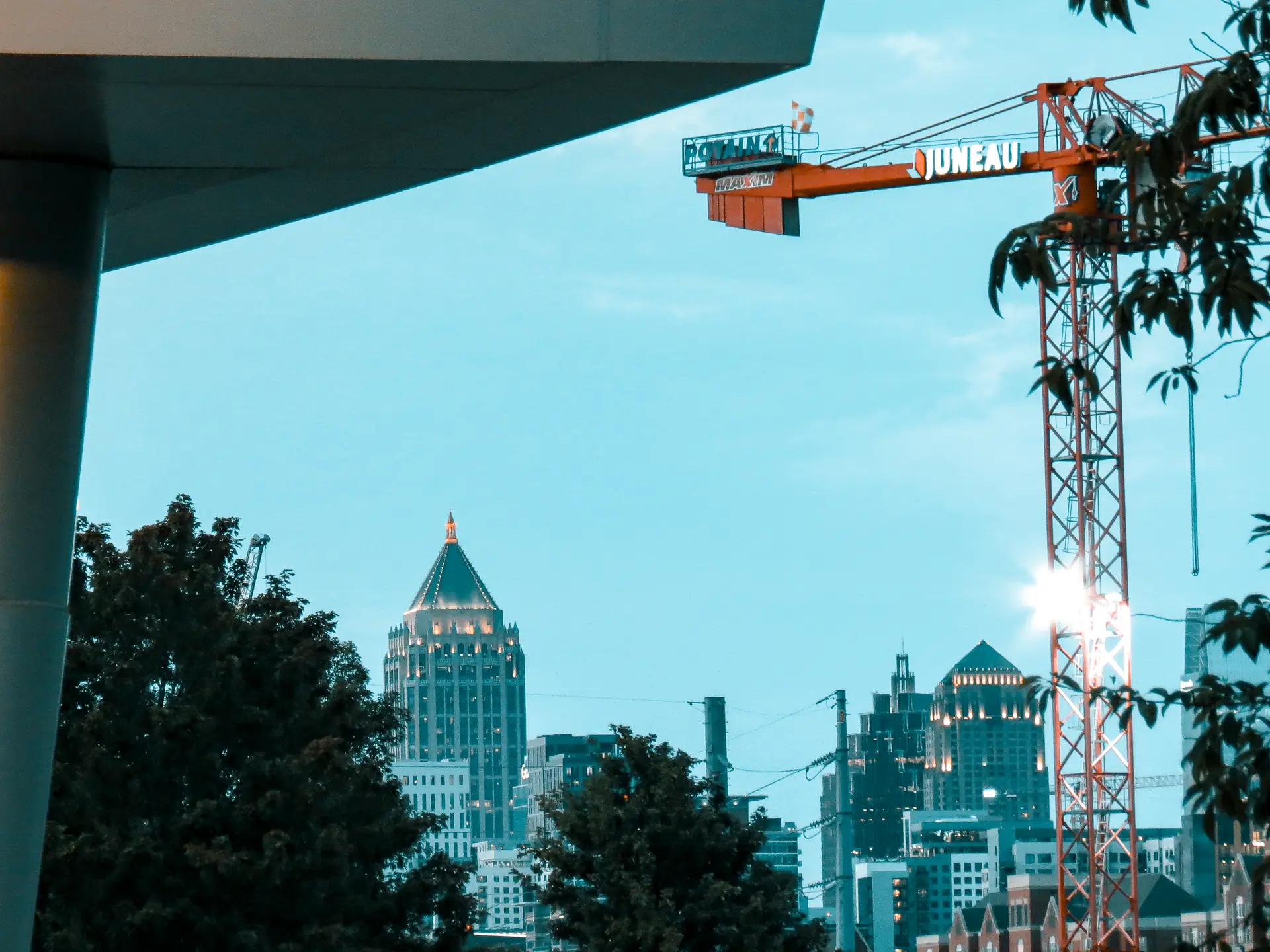 A construction crane and lit tower crowns above the Midtown Atlanta skyline at dusk